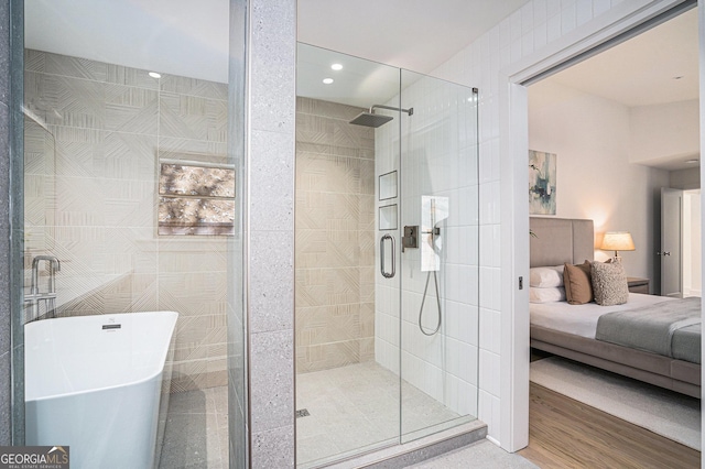 bathroom with hardwood / wood-style floors, shower with separate bathtub, and tile walls