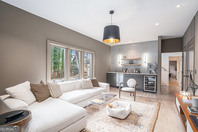 living room with light hardwood / wood-style floors, beverage cooler, and indoor bar