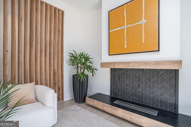 living area with a tile fireplace and light hardwood / wood-style floors