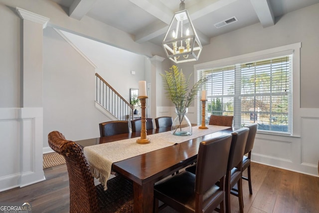 dining area featuring beam ceiling, dark wood-type flooring, a chandelier, and ornate columns