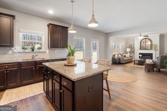 kitchen featuring pendant lighting, a center island, a kitchen bar, sink, and dark brown cabinets