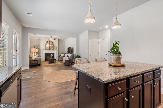 kitchen with ceiling fan, a kitchen island, stainless steel dishwasher, a breakfast bar, and dark brown cabinetry