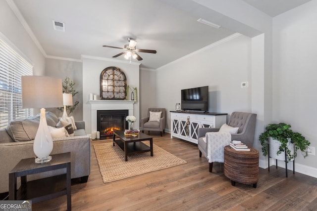 living room featuring dark wood-type flooring, crown molding, and ceiling fan