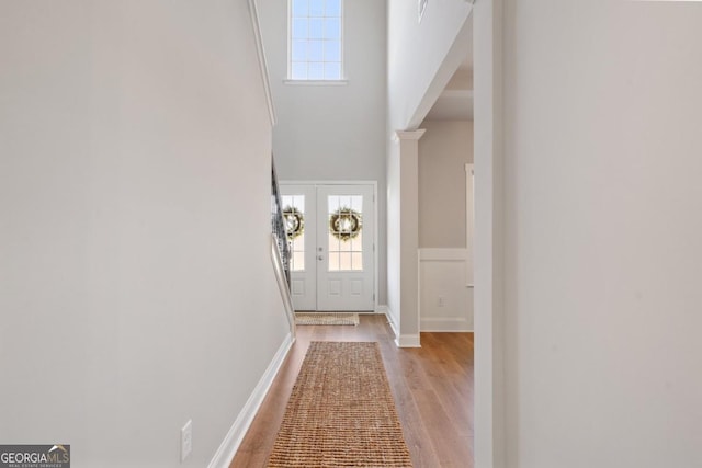 doorway to outside featuring a towering ceiling and light hardwood / wood-style flooring