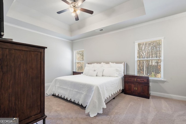 carpeted bedroom with ceiling fan, crown molding, and a tray ceiling