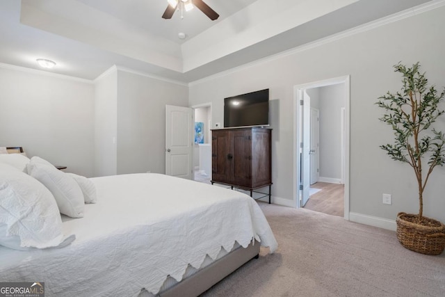 bedroom featuring ceiling fan, ensuite bath, a tray ceiling, and light carpet