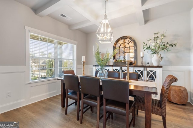 dining space with beamed ceiling, an inviting chandelier, coffered ceiling, and hardwood / wood-style flooring