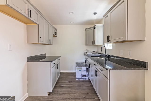 kitchen featuring sink, dark stone counters, hanging light fixtures, gray cabinetry, and dark hardwood / wood-style flooring