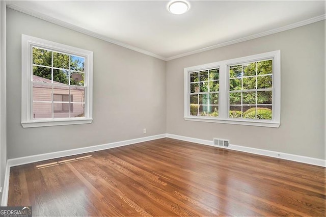 unfurnished room with crown molding, a healthy amount of sunlight, and hardwood / wood-style floors