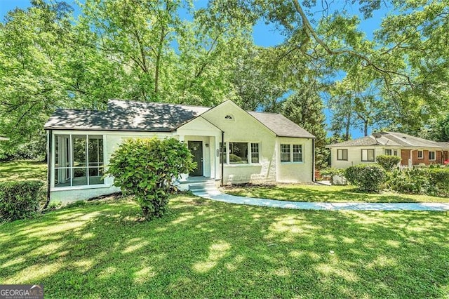 single story home featuring a front yard and a sunroom