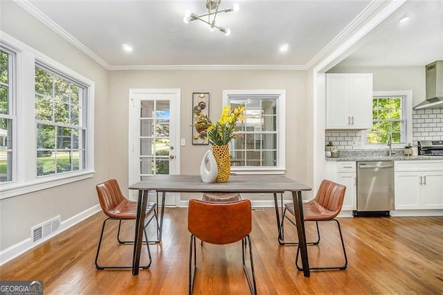 dining room featuring an inviting chandelier, crown molding, light hardwood / wood-style flooring, and sink