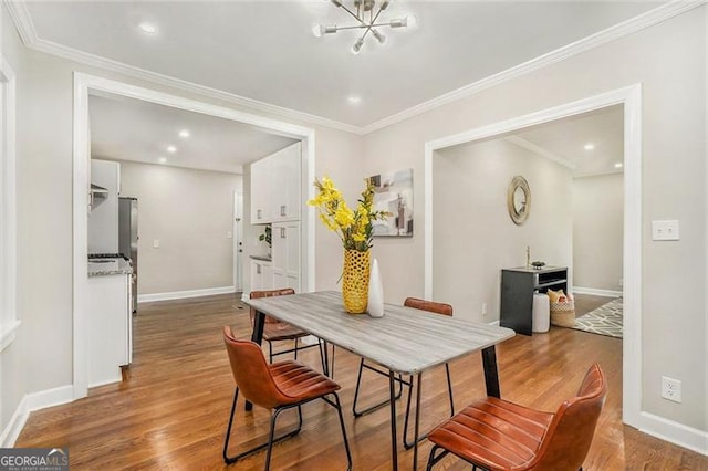 dining area featuring crown molding, wood-type flooring, and a notable chandelier