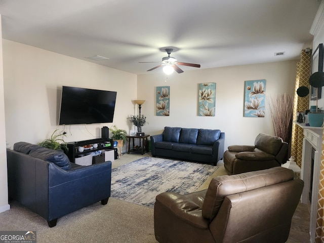 carpeted living room with ceiling fan and a tiled fireplace