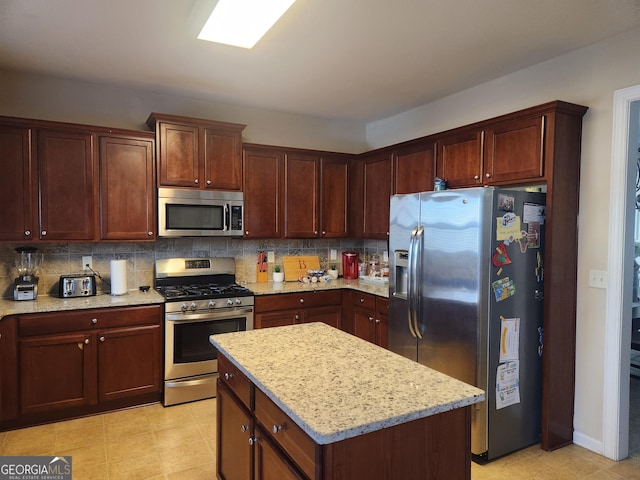 kitchen featuring tasteful backsplash, stainless steel appliances, light stone counters, and a kitchen island