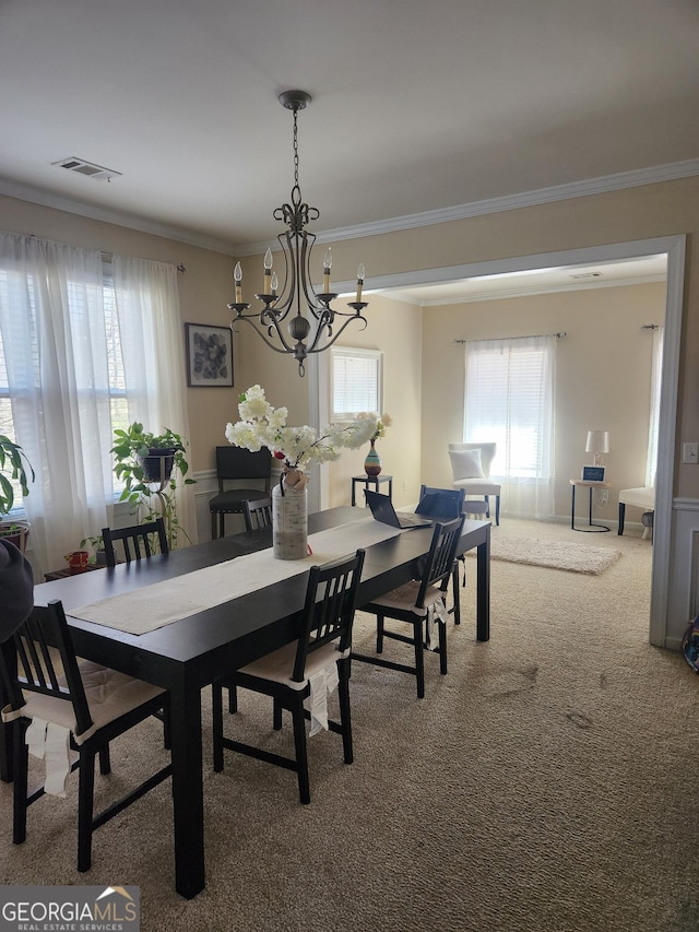 carpeted dining space featuring crown molding and a chandelier