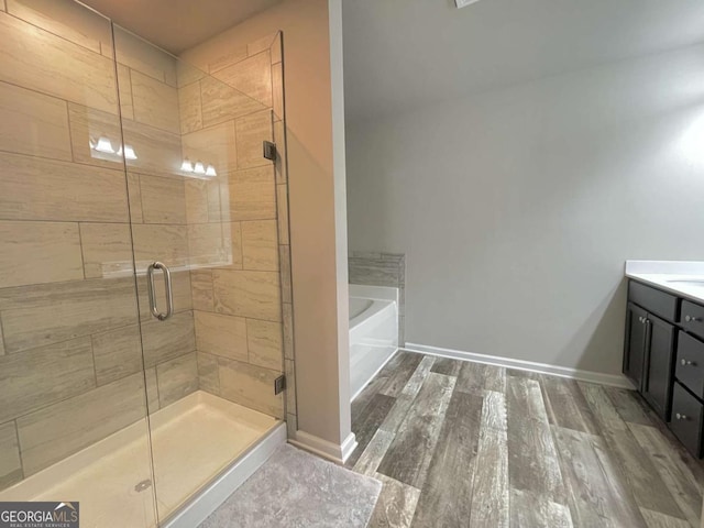 bathroom featuring vanity, wood-type flooring, and plus walk in shower