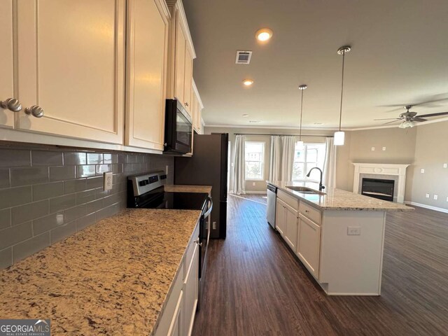 kitchen featuring light stone countertops, stainless steel appliances, tasteful backsplash, an island with sink, and sink