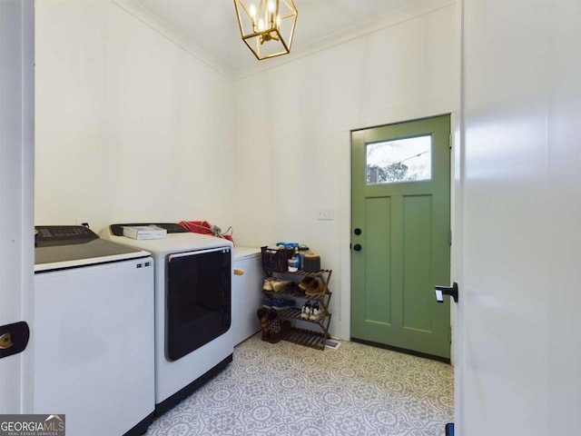 clothes washing area featuring a notable chandelier, washer and dryer, and ornamental molding