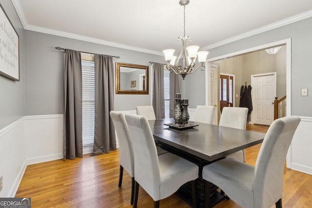 dining space with a notable chandelier, plenty of natural light, crown molding, and hardwood / wood-style floors