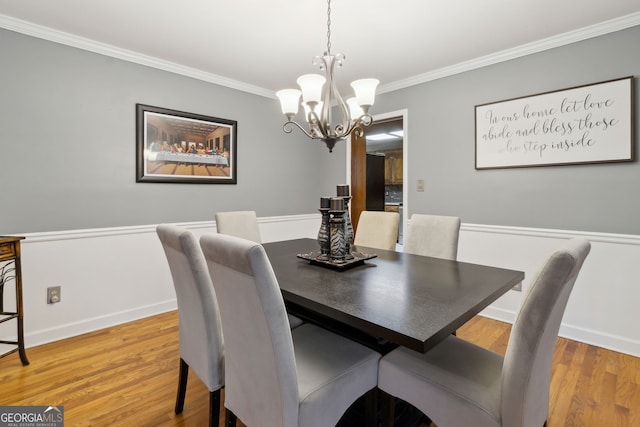 dining space featuring an inviting chandelier, crown molding, and hardwood / wood-style floors