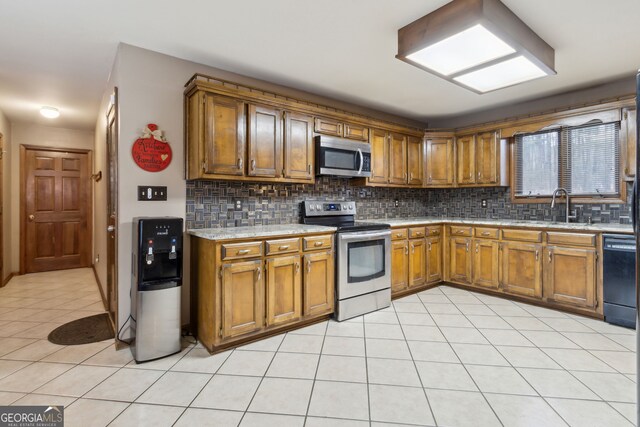 kitchen with light tile patterned floors, stainless steel appliances, tasteful backsplash, and sink