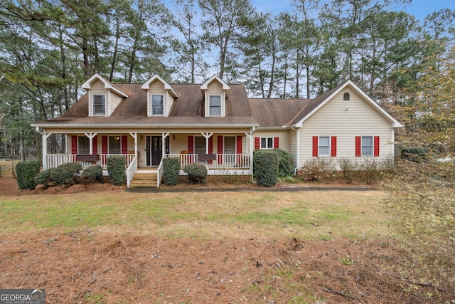 cape cod home featuring covered porch and a front lawn