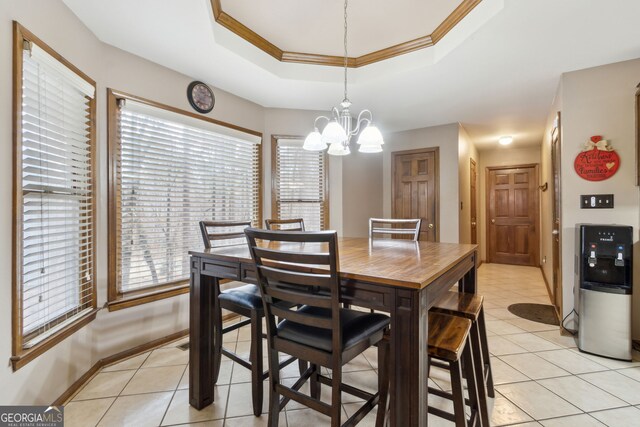 tiled dining space featuring crown molding, a tray ceiling, and a notable chandelier