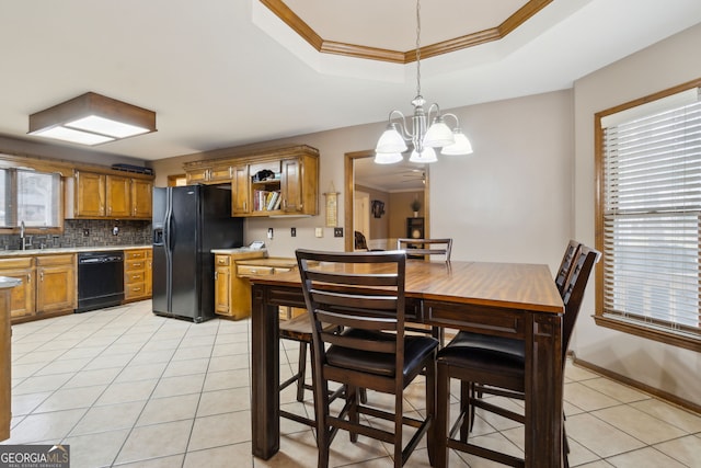 tiled dining space featuring a raised ceiling, an inviting chandelier, sink, and crown molding