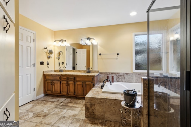 bathroom with tiled tub and vanity