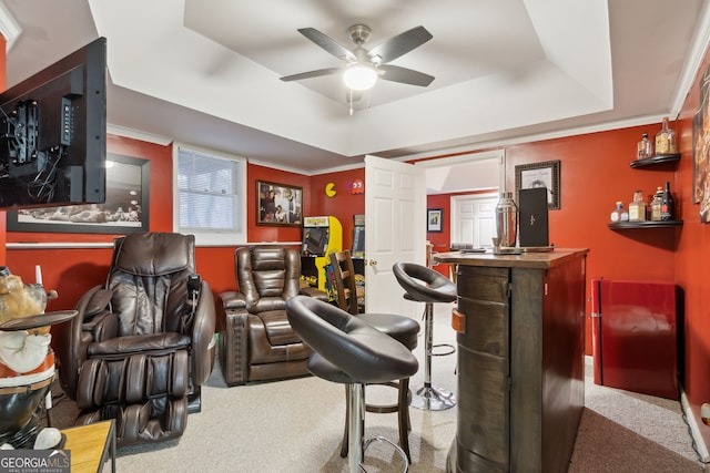 bar with light carpet, ceiling fan, crown molding, and a tray ceiling