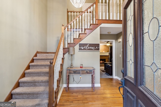 entrance foyer featuring a towering ceiling, a healthy amount of sunlight, a fireplace, and wood-type flooring