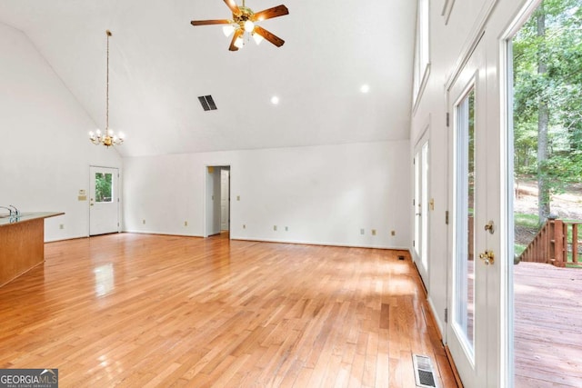 unfurnished living room featuring high vaulted ceiling, light hardwood / wood-style floors, and ceiling fan with notable chandelier