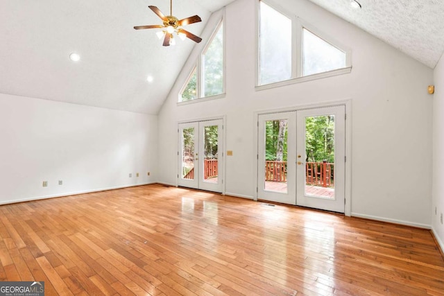 unfurnished living room with high vaulted ceiling, ceiling fan, light hardwood / wood-style flooring, and french doors