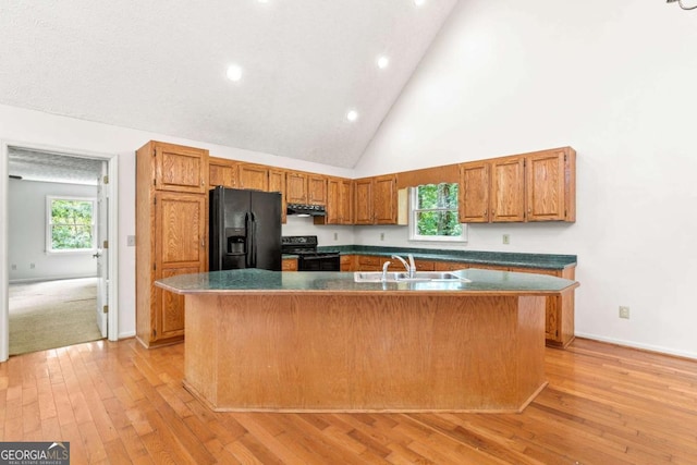 kitchen with an island with sink, electric range, black refrigerator with ice dispenser, high vaulted ceiling, and sink