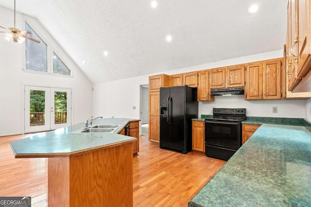 kitchen featuring a center island with sink, french doors, black appliances, light hardwood / wood-style flooring, and sink