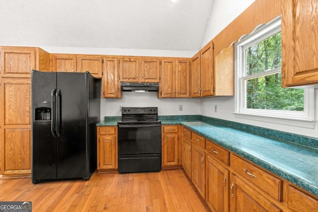 kitchen featuring vaulted ceiling, light hardwood / wood-style flooring, and black appliances