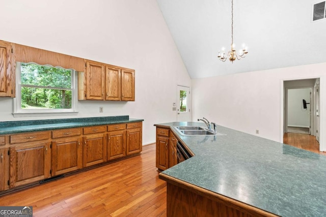 kitchen with sink, black dishwasher, light hardwood / wood-style flooring, high vaulted ceiling, and a chandelier