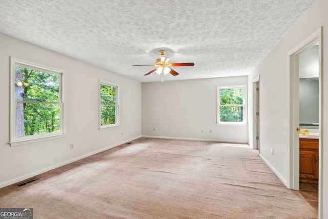 carpeted empty room with ceiling fan and a textured ceiling