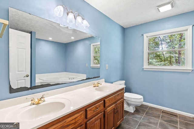 bathroom featuring toilet, a wealth of natural light, a textured ceiling, and vanity