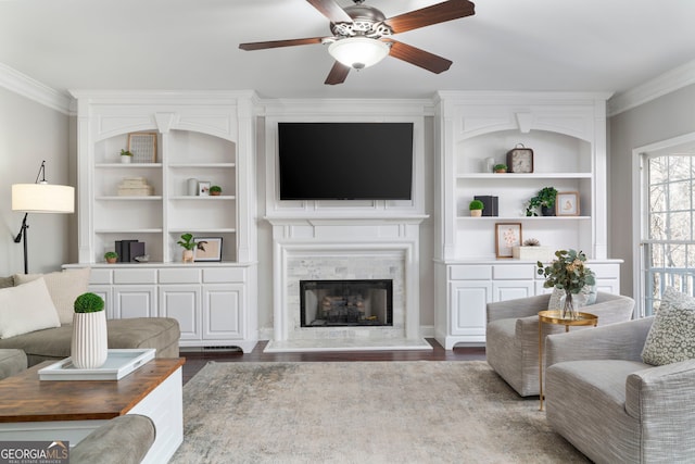 living room with ornamental molding, wood-type flooring, ceiling fan, and built in shelves