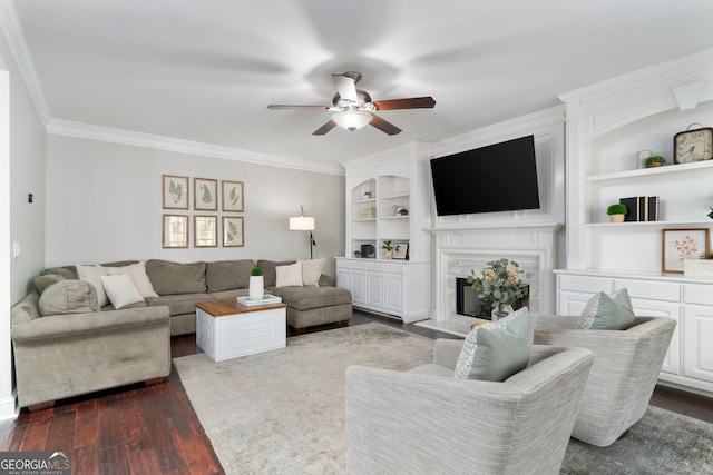 living room featuring dark hardwood / wood-style floors, built in features, crown molding, ceiling fan, and a premium fireplace