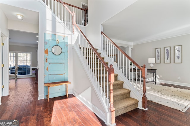 stairway featuring hardwood / wood-style flooring, ornamental molding, and a high ceiling