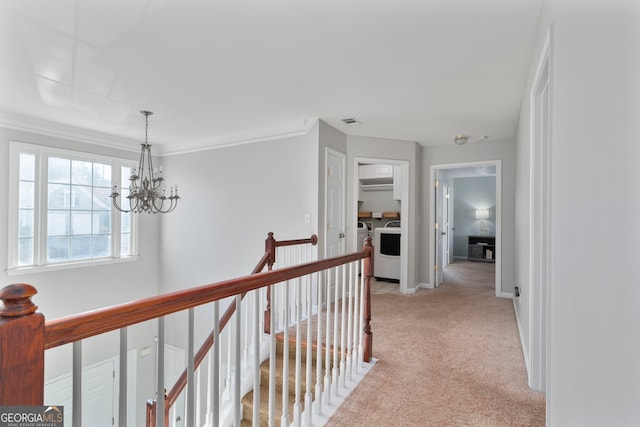 corridor featuring an inviting chandelier, ornamental molding, and light colored carpet