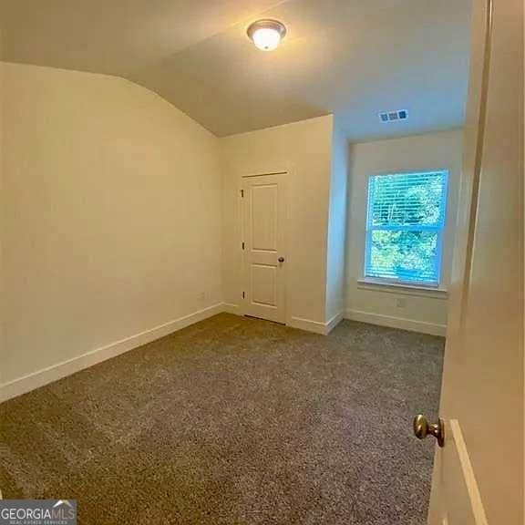 bonus room featuring vaulted ceiling and dark carpet