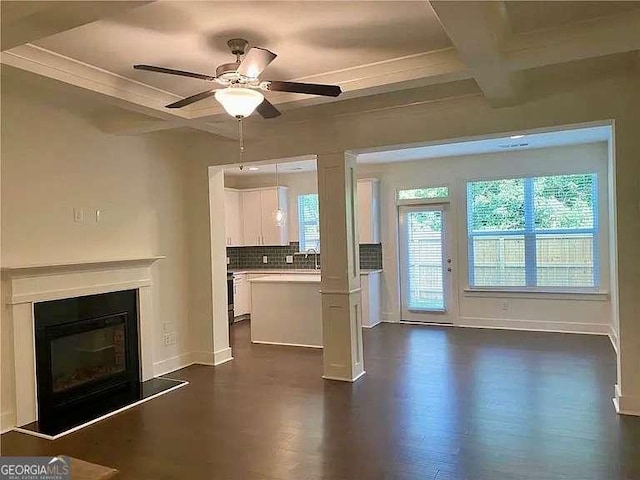 unfurnished living room with ceiling fan, beam ceiling, sink, crown molding, and coffered ceiling