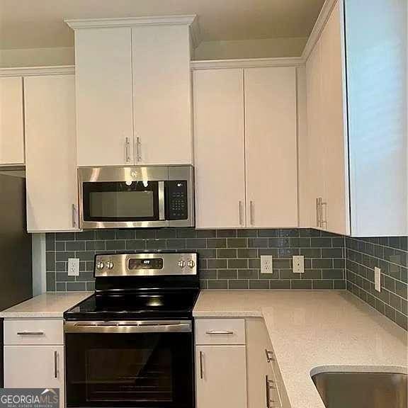 kitchen with backsplash, white cabinets, and range with electric cooktop