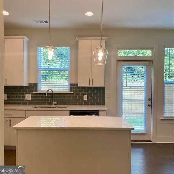 kitchen featuring sink, a kitchen island, white cabinetry, and pendant lighting