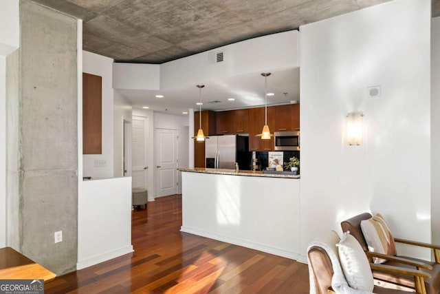 kitchen featuring appliances with stainless steel finishes, stone countertops, hanging light fixtures, dark hardwood / wood-style floors, and kitchen peninsula