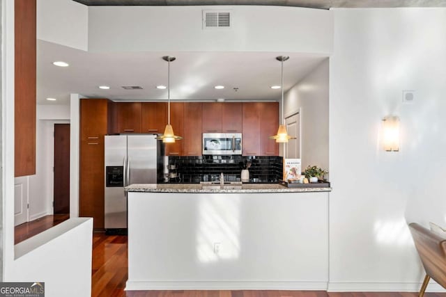 kitchen featuring wood-type flooring, hanging light fixtures, sink, light stone countertops, and stainless steel appliances