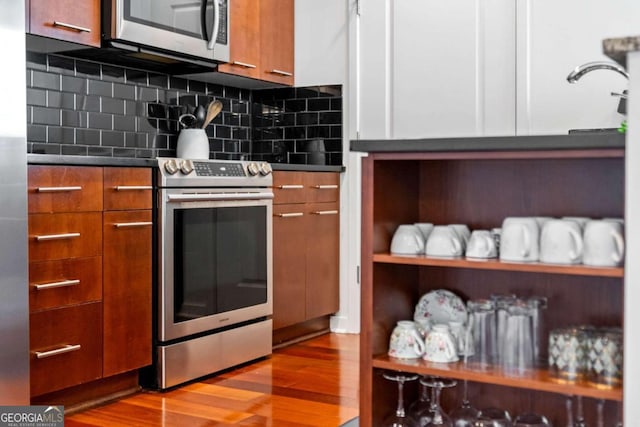 kitchen with decorative backsplash, light hardwood / wood-style floors, white cabinetry, and stainless steel appliances